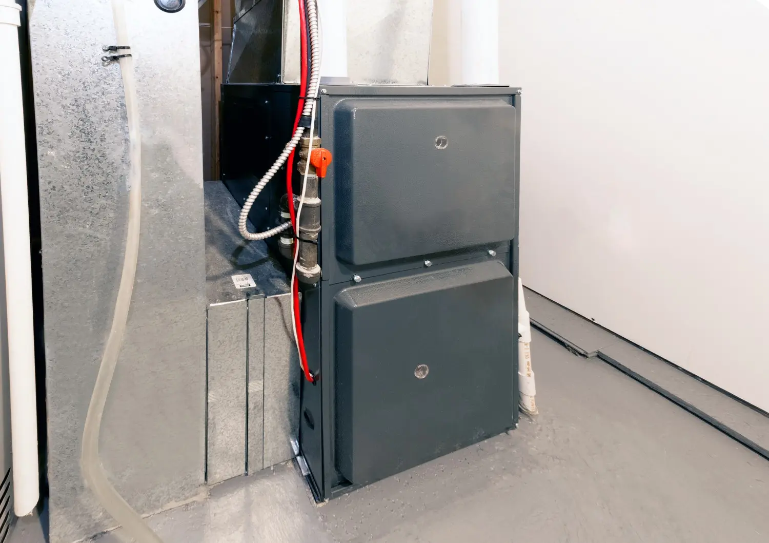 A modern gray gas furnace unit installed in a utility closet or basement.