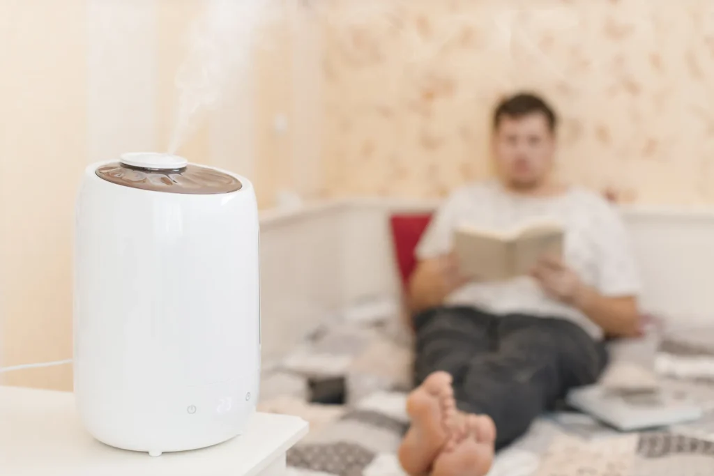 A humidifier on the table in a living room, with a person sitting nearby